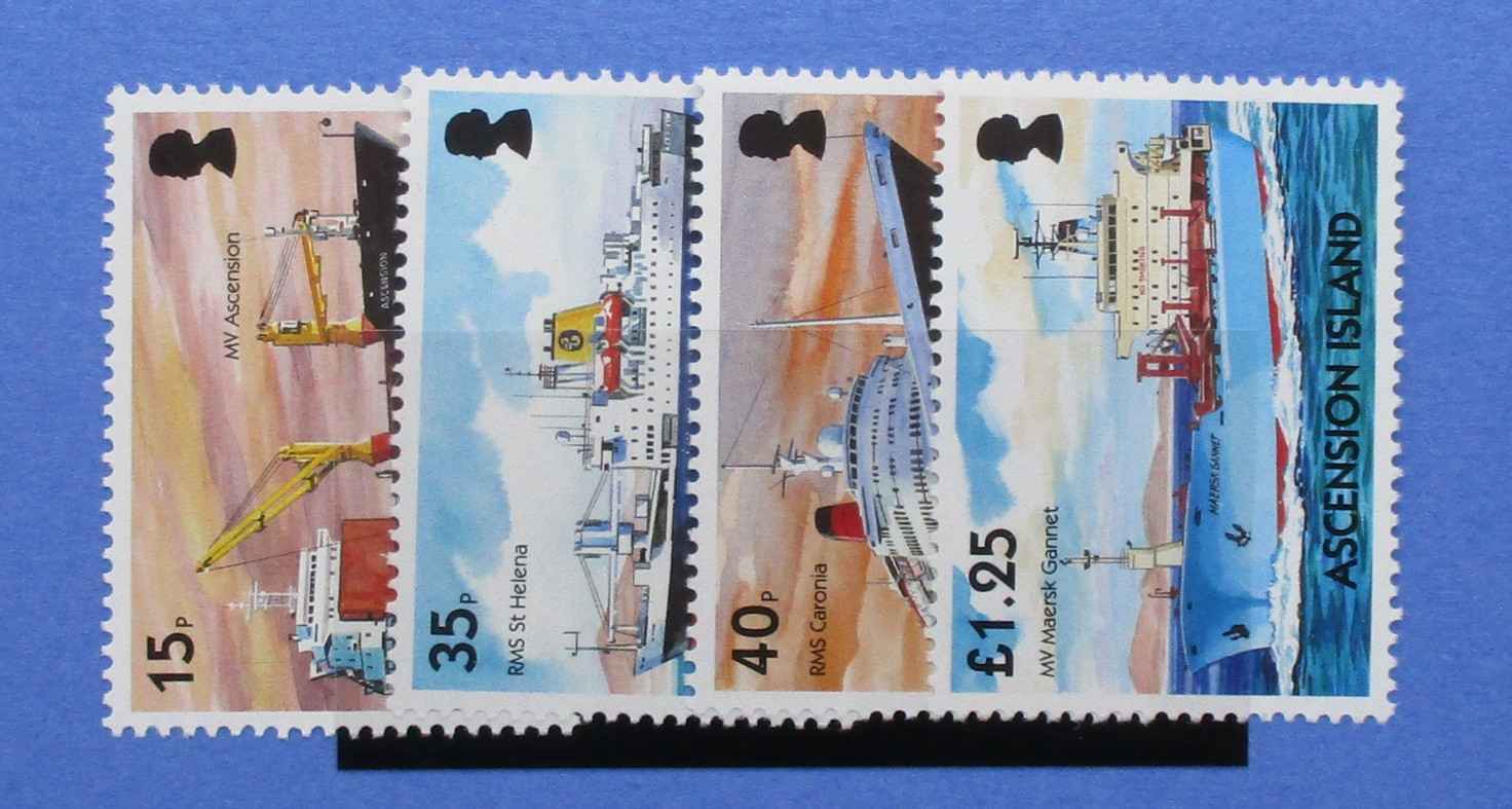 Four postage stamps from Ascension Island featuring illustrations of ships and port equipment, displayed side by side on a blue background.