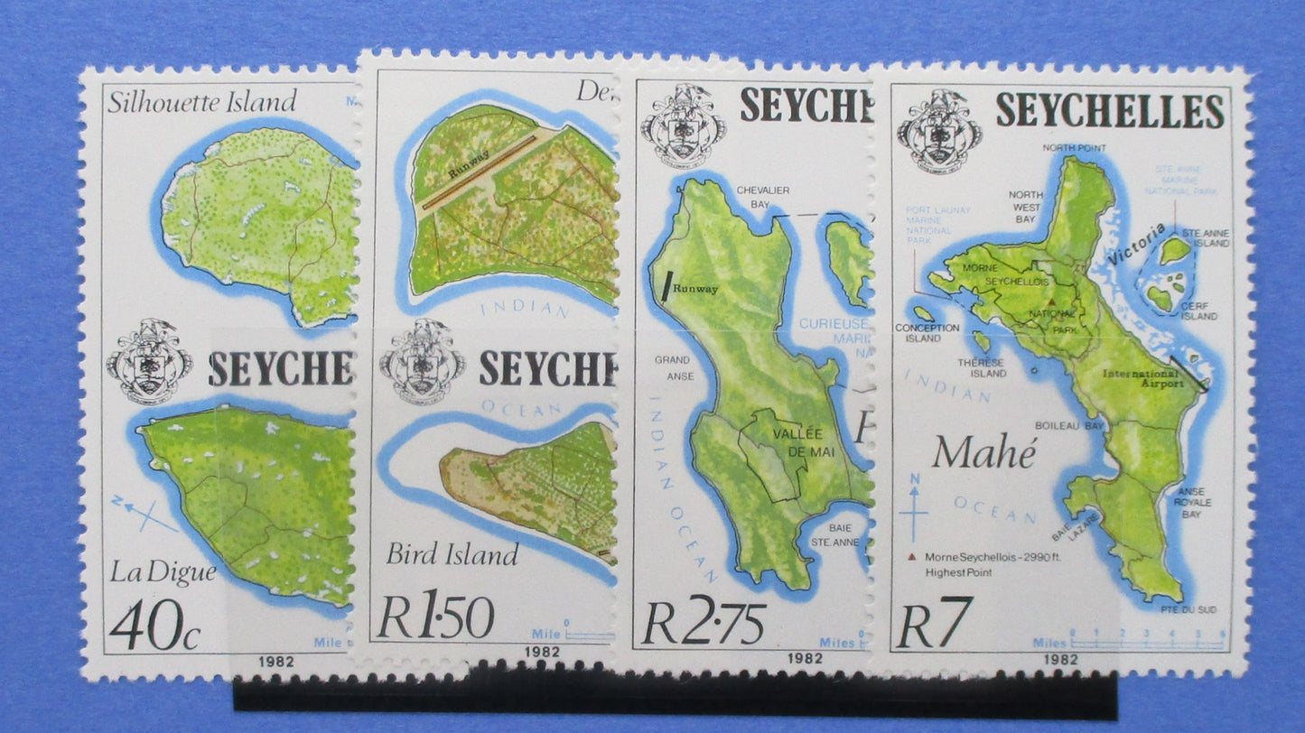 Four vintage Seychelles postage stamps displayed side by side on a blue background. The stamps feature illustrated maps of Seychelles islands, including La Digue, Bird Island, and Mahé, with denominations 40c, R1.50, R2.75, R7