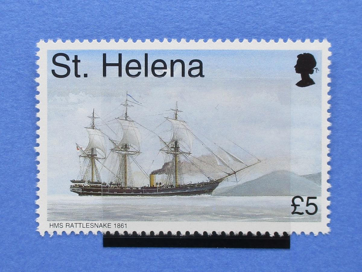 A rectangular postage stamp with perforated edges featuring an illustration of a three-masted sailing ship on water, with the text 'St. Helena', 'HMS RATTLESNAKE 1861', and a black Queen's silhouette in the upper right.