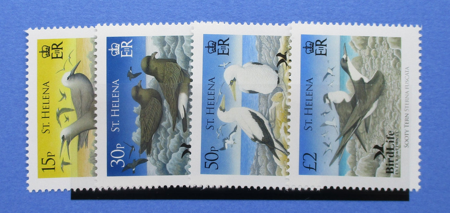 Four St. Helena postage stamps with bird illustrations, displayed side by side on a blue background.