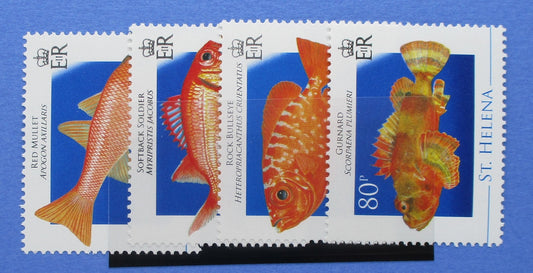 Four postage stamp sheets featuring colorful fish illustrations on a blue background, with 'St. Helena' and '80p' visible on the stamps.